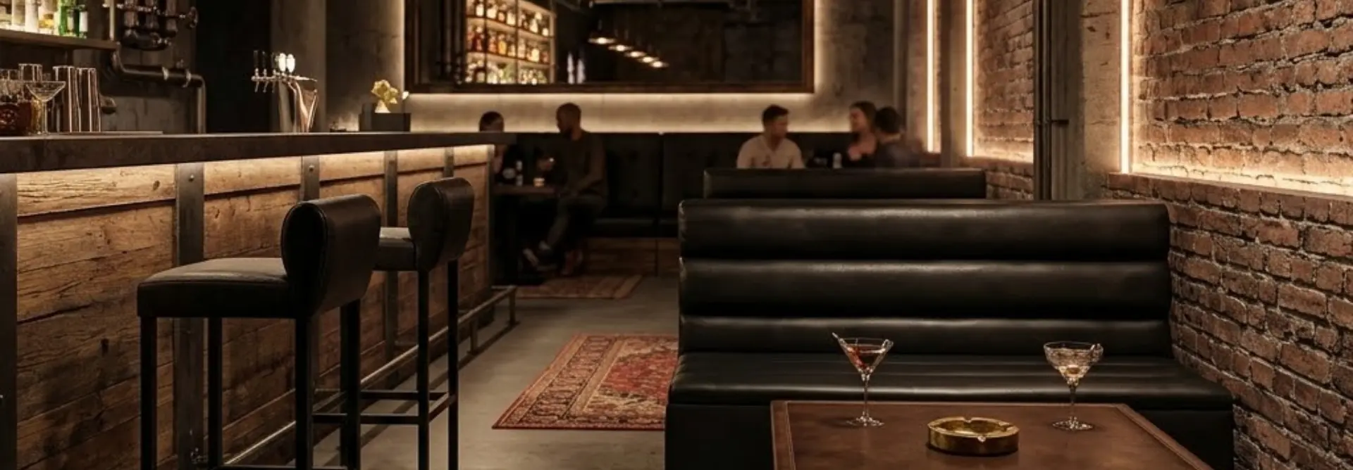 Interno di un bar elegante in stile speakeasy con bancone in legno, sgabelli in pelle, divanetti neri, pareti in mattoni a vista e luci soffuse.